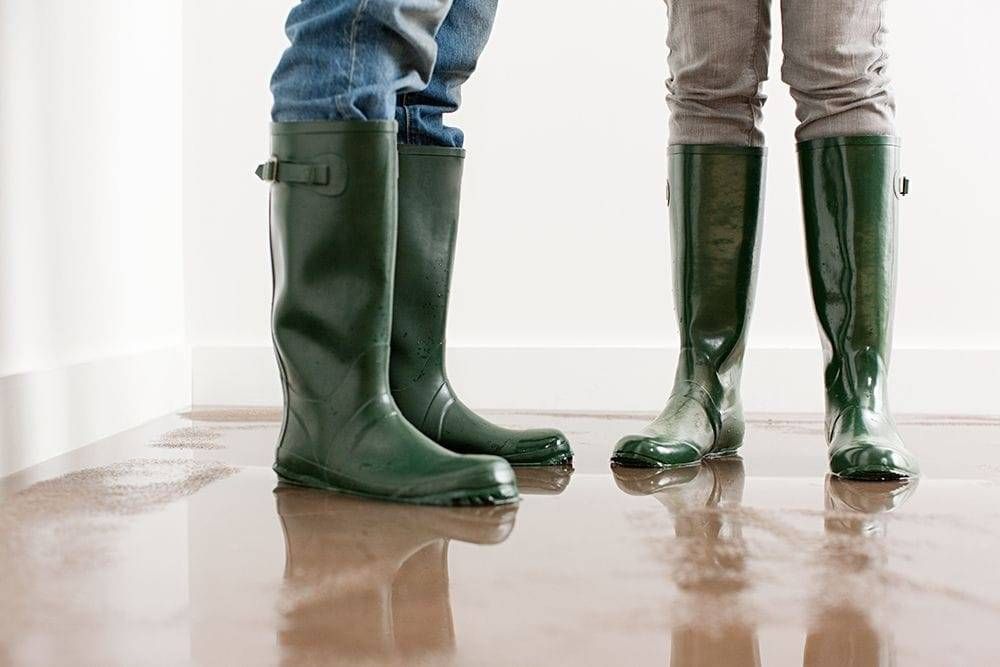 Technicians wearing green rubber boots on a wet floor.