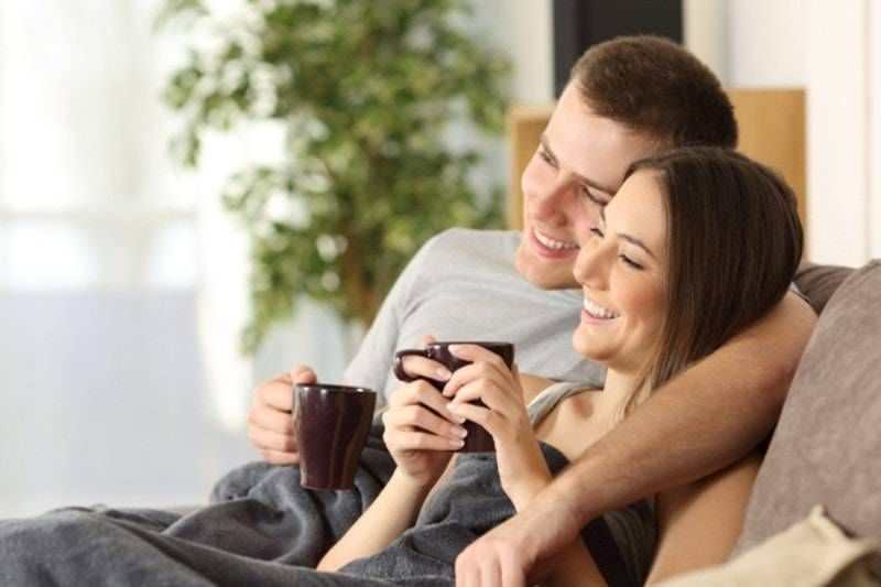Smiling couple on a couch with their well-maintained furnace system in Fort Collins.