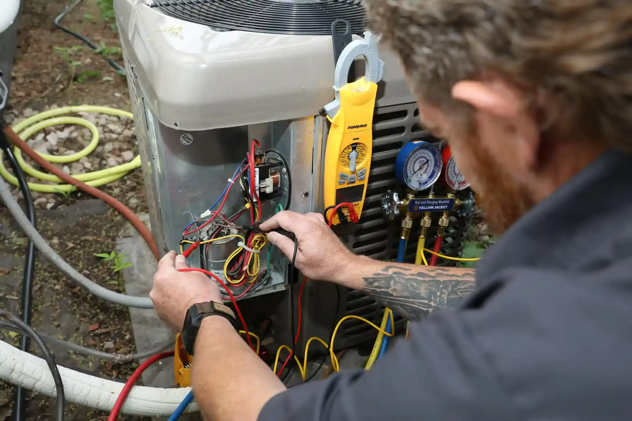 HVAC technician uses a Fieldpiece clamp meter and probes to test and repair components of a heat pump unit.