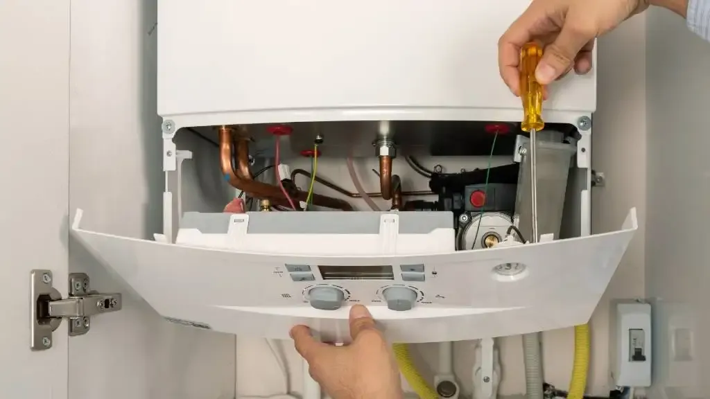 HVAC technician fixing the internal components of a boiler.