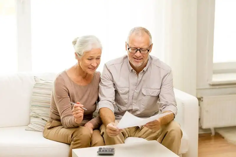 Elderly couple examining possible costs for repair on a not well-maintained furnace.