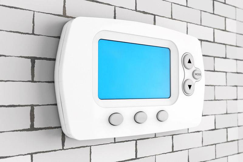 Digital thermostat with a blue screen and three buttons displayed on a brick-patterned wall.