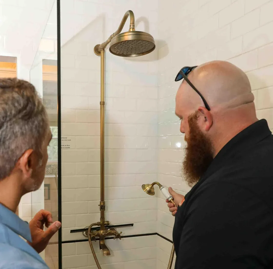 Plumber testing water flow from a bathroom faucet after completing shower installation.