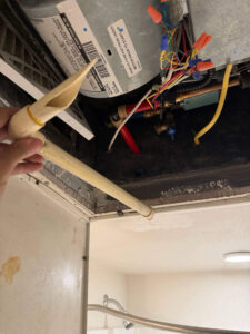Fort Collins AC repair technician repairing a condensate drain line inside an indoor air handler to restore proper drainage