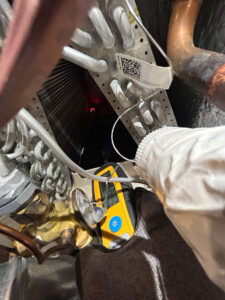Fort Collins AC repair technician using an electronic leak detector inside an outdoor unit to locate a refrigerant leak and restore cooling