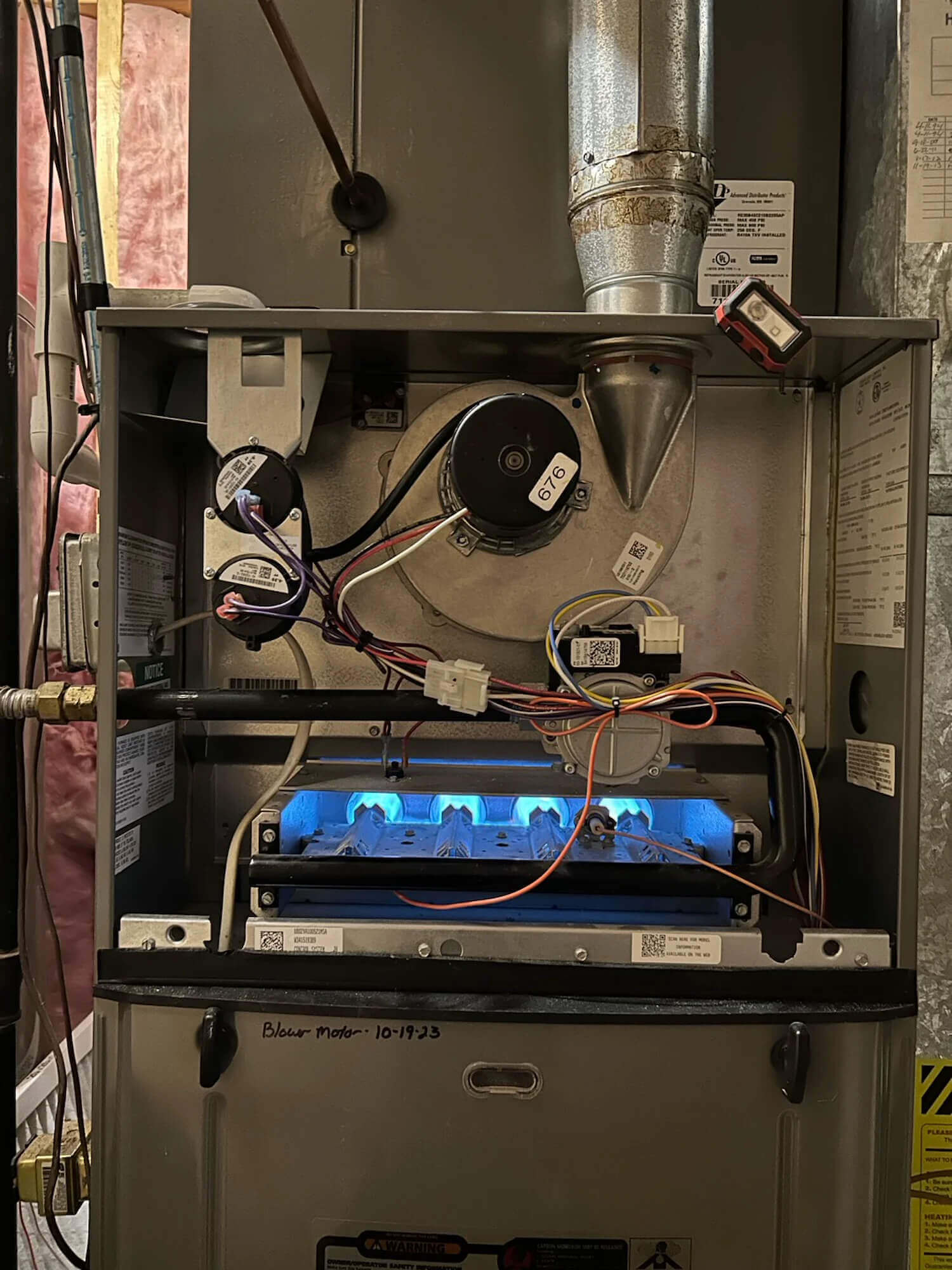 Open furnace cabinet showing blue burner flames and blower motor during a service call in a Fort Collins home served by Balance Point Heating, Cooling & Plumbing