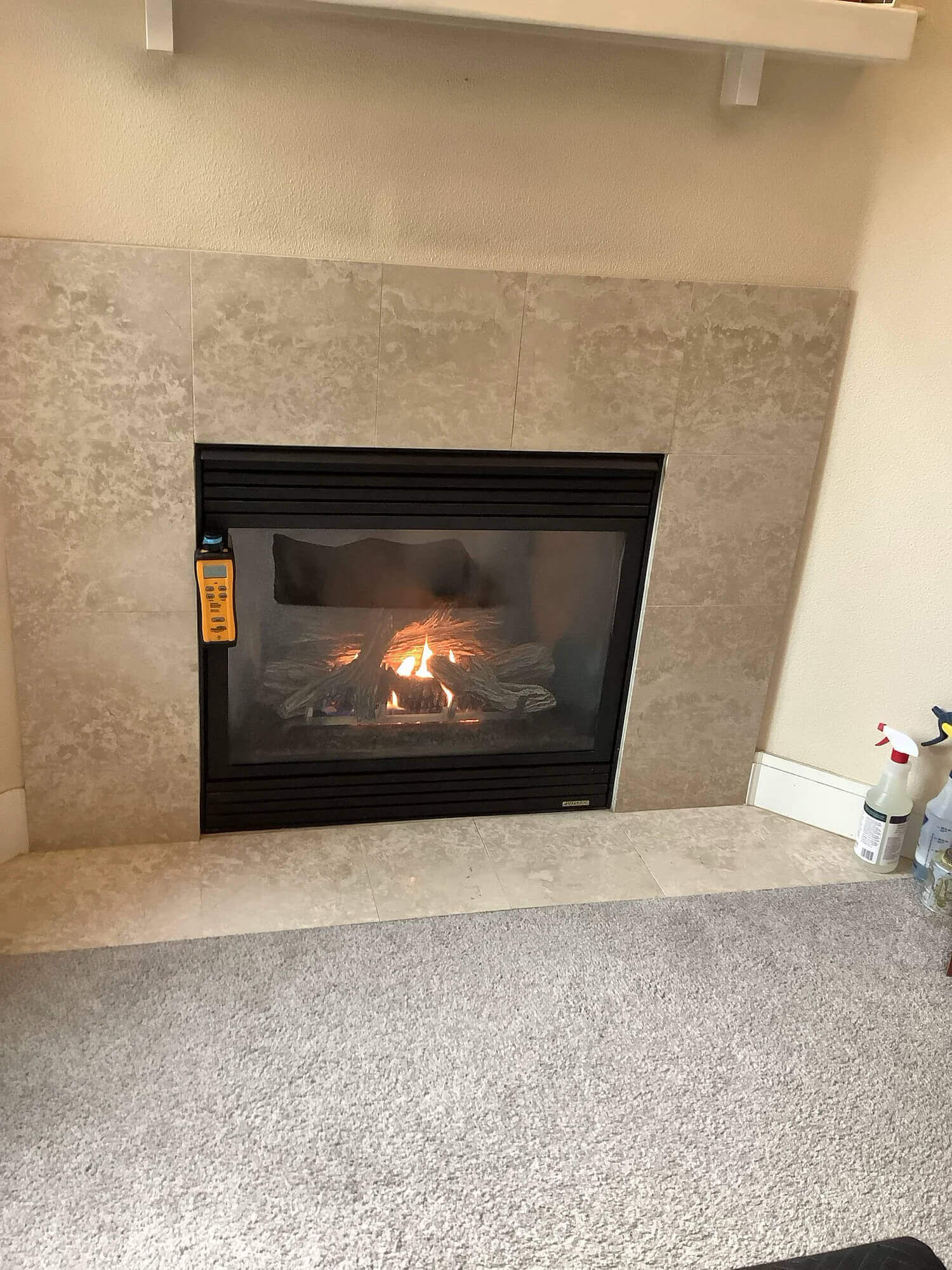 Technician inspecting a gas fireplace with a combustion analyzer in a customer's home.