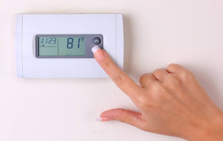 thermostat. woman's hand setting the room temperature on a modern programmable wall heater. closeup, How to Set Your Programmable Thermostat