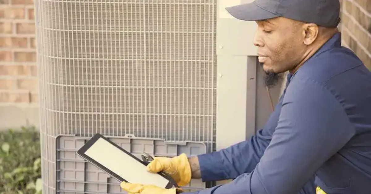 HVAC technician uses a tablet while inspecting an outdoor HVAC unit in a Colorado home.