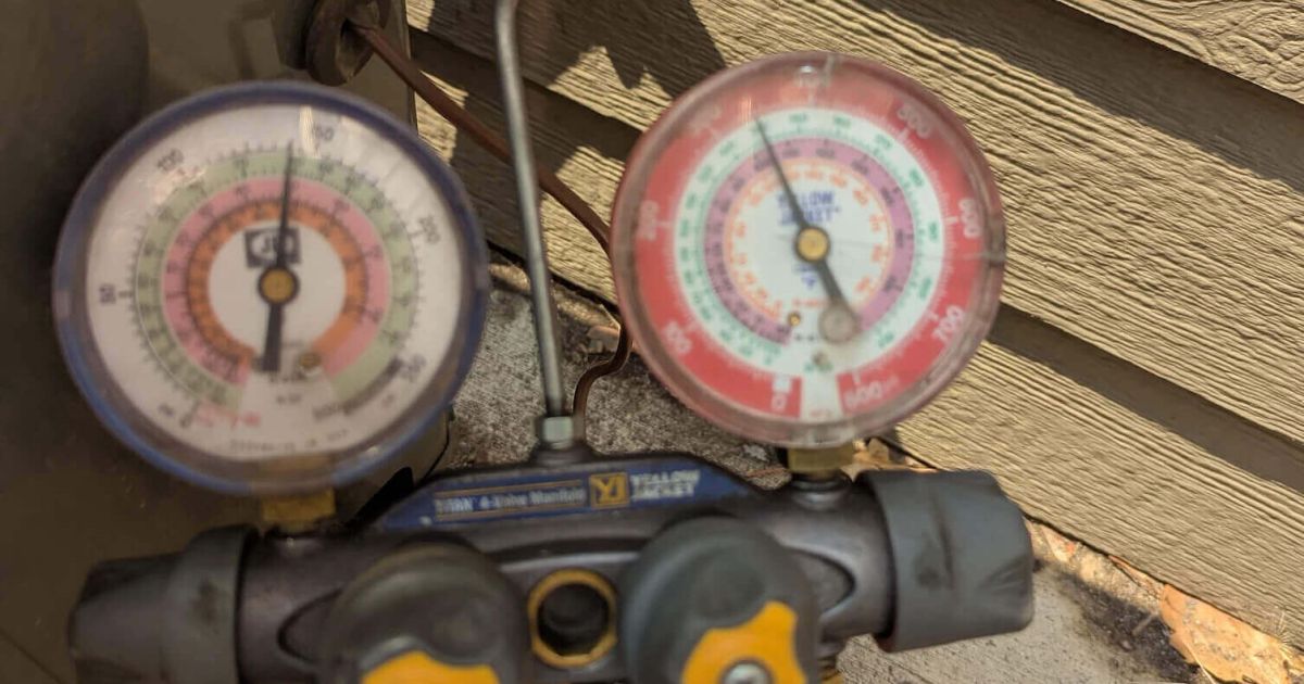 Technician checking AC refrigerant pressure with manifold gauges outside a Fort Collins home served by Balance Point Heating, Cooling & Plumbing