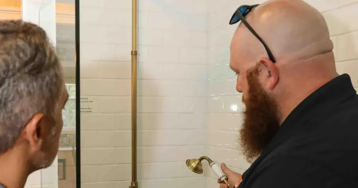 Plumber testing water flow from a bathroom faucet after completing shower installation.