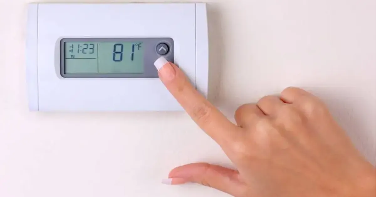 Hand adjusting the temperature on a thermostat in Fort Collins home.