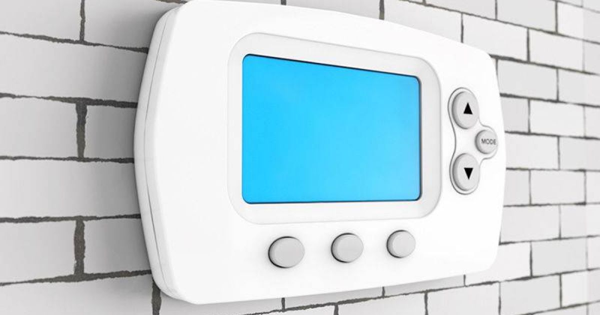 Digital thermostat with a blue screen and three buttons displayed on a brick-patterned wall.
