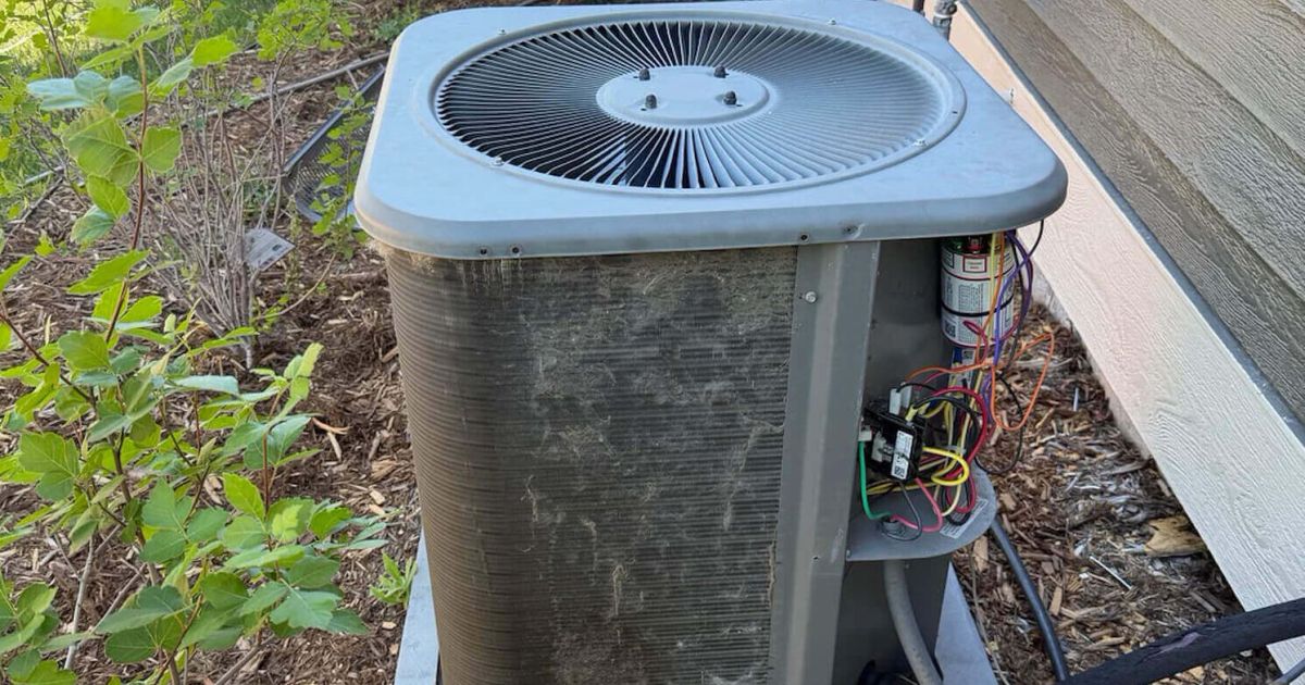 Dirty AC condenser unit with buildup on the coils outside a Fort Collins home served by Balance Point Heating, Cooling & Plumbing