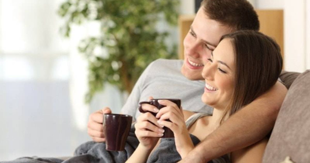 Smiling couple on a couch with their well-maintained furnace system in Fort Collins.