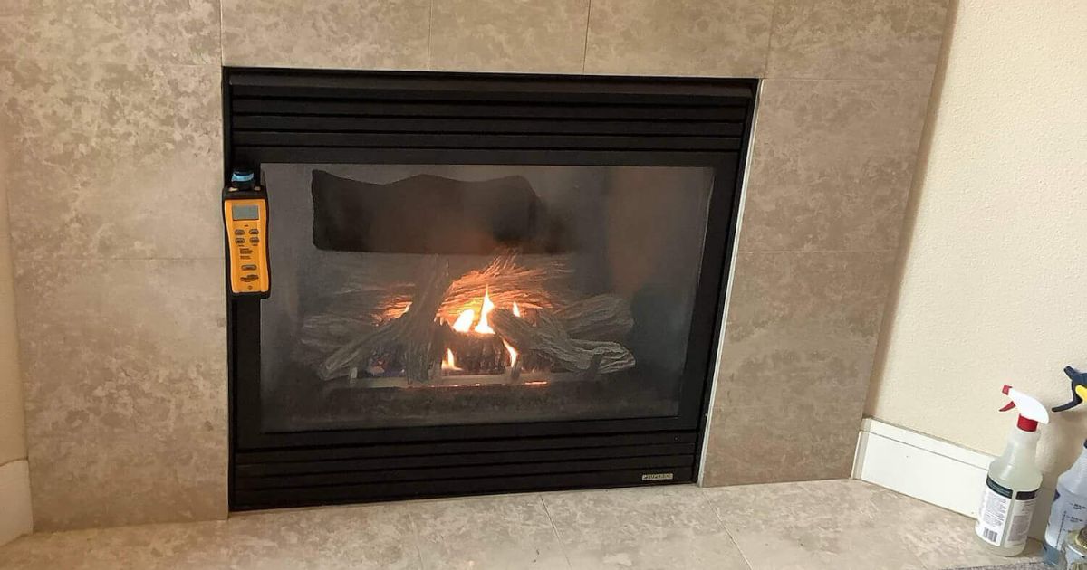 Technician inspecting a gas fireplace with a combustion analyzer in a customer's home.